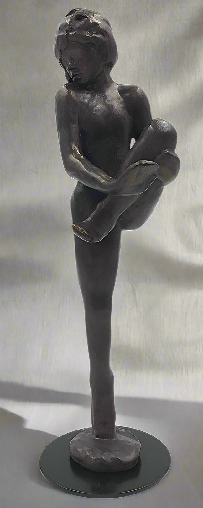 Bronze sculpture of a standing figure with arms crossed on a black base